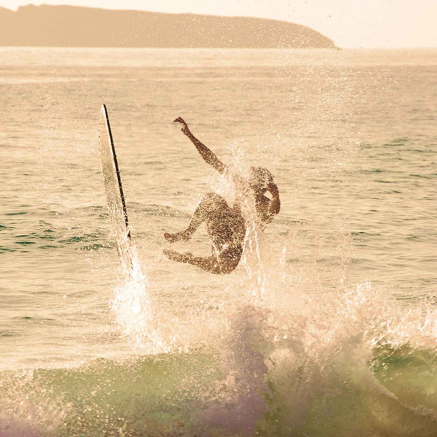 Person wakeboarding on a body of water with a sunset or sunrise in the background